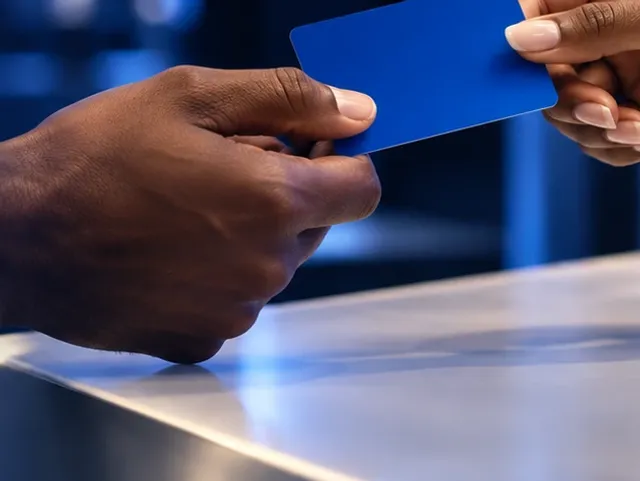 Hand passing a bank card across a desk